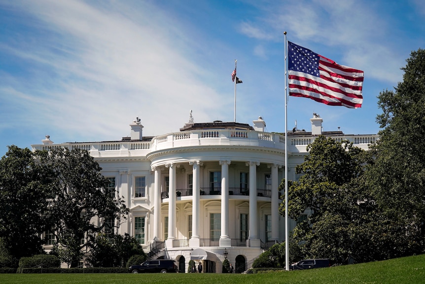 An American flag flying out the front of the White House in Washington DC on a sunny day.