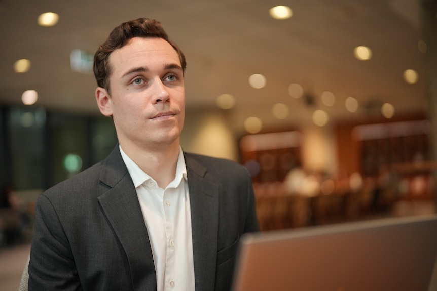 Lochlan Holloway seated in front of a laptop