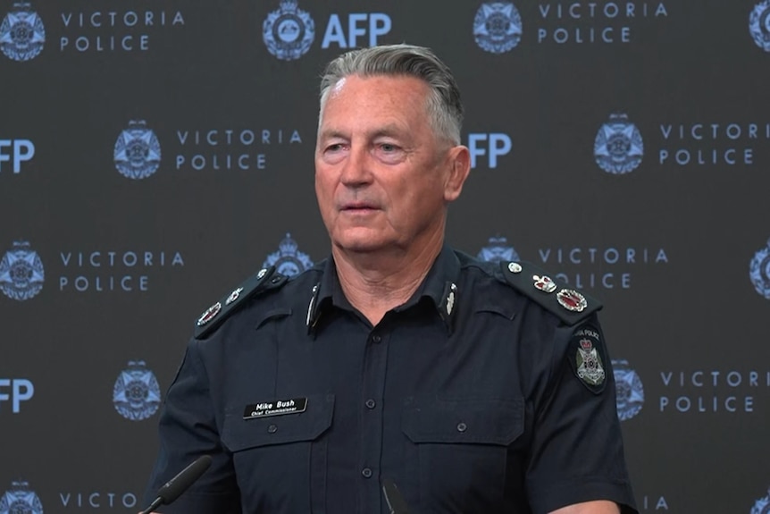 A police commissioner standing in front of the AFP sign.