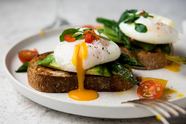 Poached eggs on toast with avocado, asparagus, tomatoes and sprout for healthy breakfast.