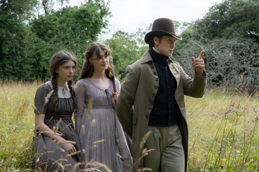A young girl and a woman walks with a man through grass