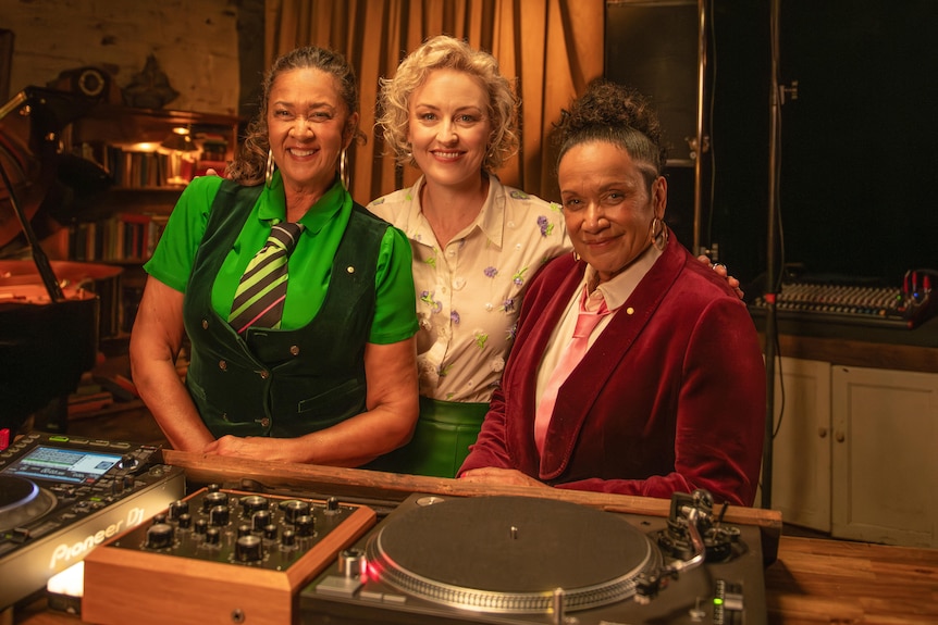 Music journalist Zan Rowe poses between Tongan-Australian singers Vika & Linda Bull at turntable backstage