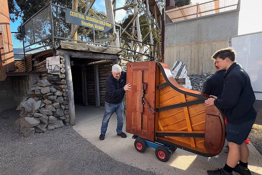 People move a piano towards a mine entrance