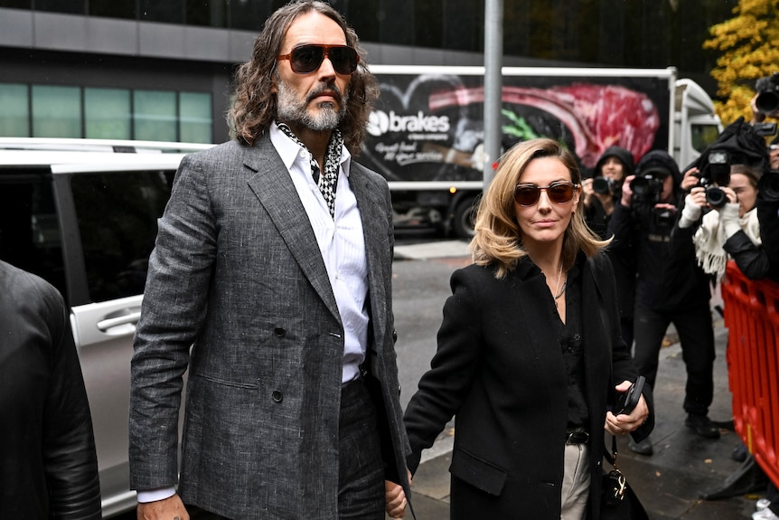 A man and woman hold hands on the street