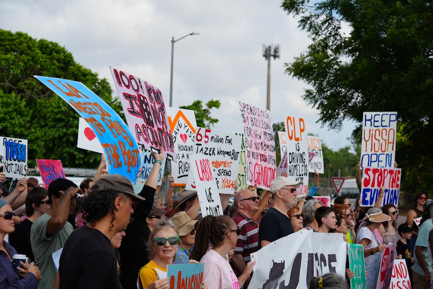 A group of about two dozen protesters holding signs outdoors.