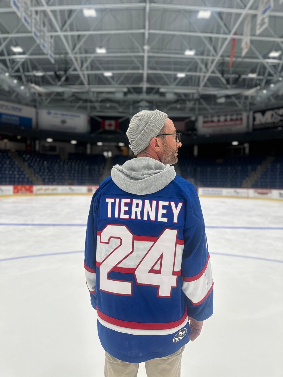 Person wearing a blue hockey jersey with "TIERNEY" and the number "24," standing on an ice rink. Person wearing a blue hockey jersey with "TIERNEY" and the number "24," standing on an ice rink.