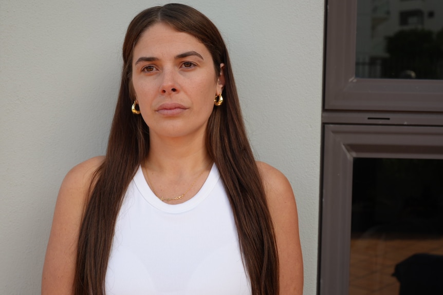 Tess Hassell stands in front of a wall as she looks sideways