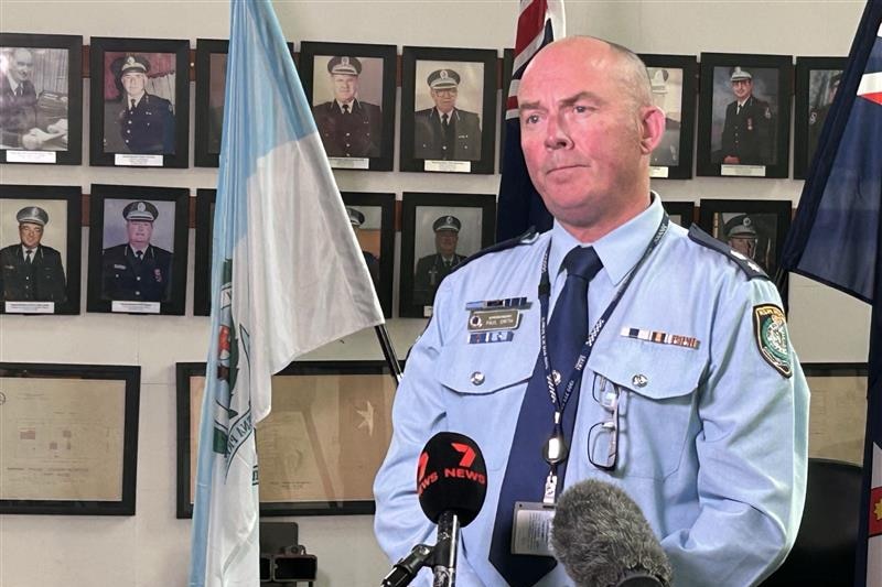Police officer standing in front of media microphones