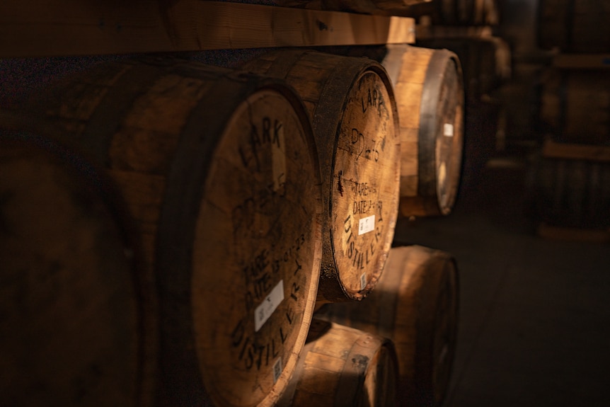 Dusty barrels and a warm coloured copper still in large shed
