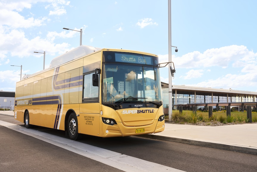 An image of a big yellow bus driving on a road.