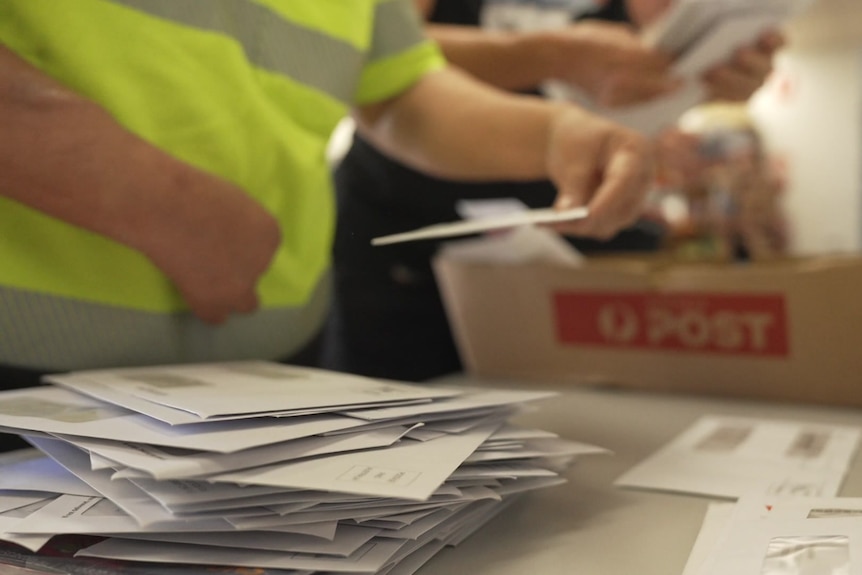 A close-up of mail handlers sorting through letters.