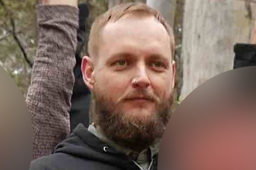 A man smiles in a social media photo with other faces blurred.