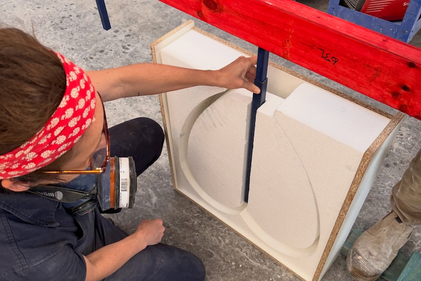 a sculture works with cement to create love hearts