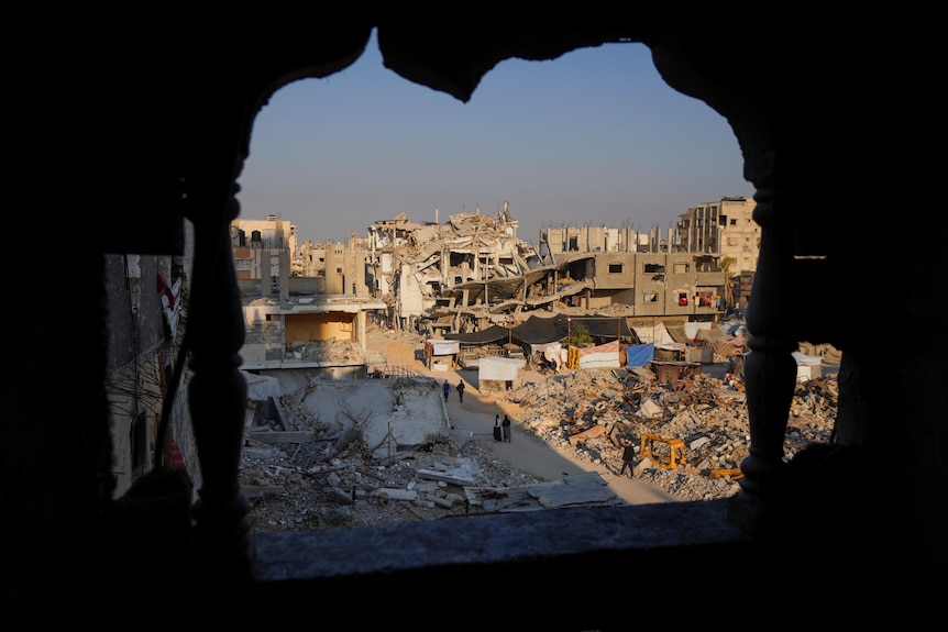 People walking through destruction in southern Gaza after an Israeli attack.