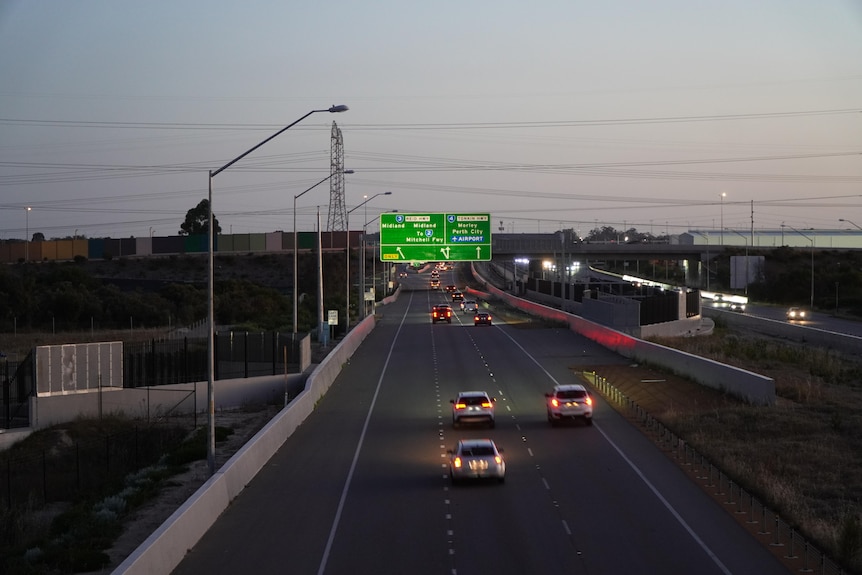 Cars drive on Tonkin Highway at dusk