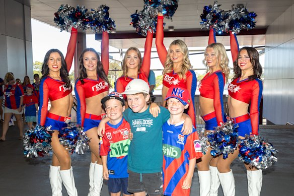 Newcastle Knights fans pose for photos with cheerleaders at a training session at McDonald Jones Stadium.