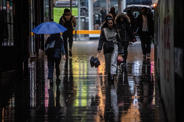 People on their way to work in Melbourne on Wednesday as the rain starts to hit.