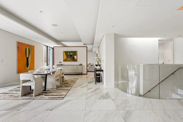 Design details include marble floors and a chic white palette that extends into the kitchen and dining zone.