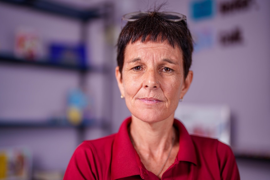 A woman with short hair looks into camera with a serious expression.