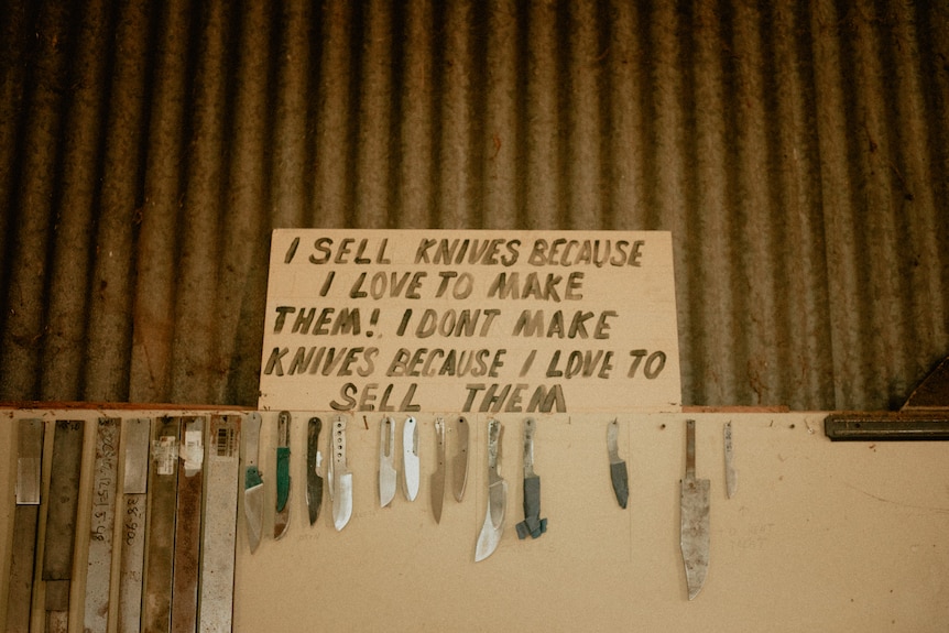 A sign reads reads "I sell knives because I love them! I don't make knives because I love to sell them"