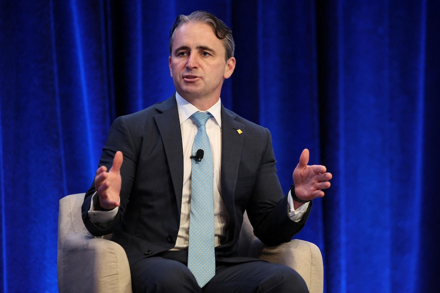 Matt Comyn, wearing a suit and tie, gestures with his hands.