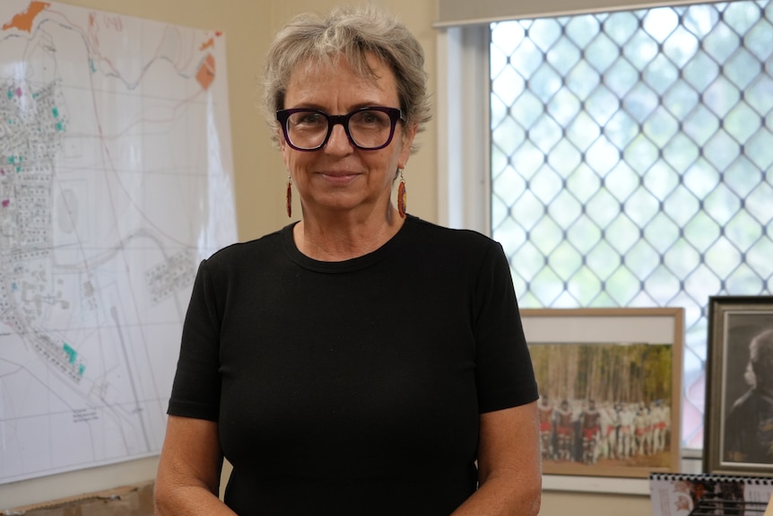 A woman with short hair wearing a black shirt standing in an office.