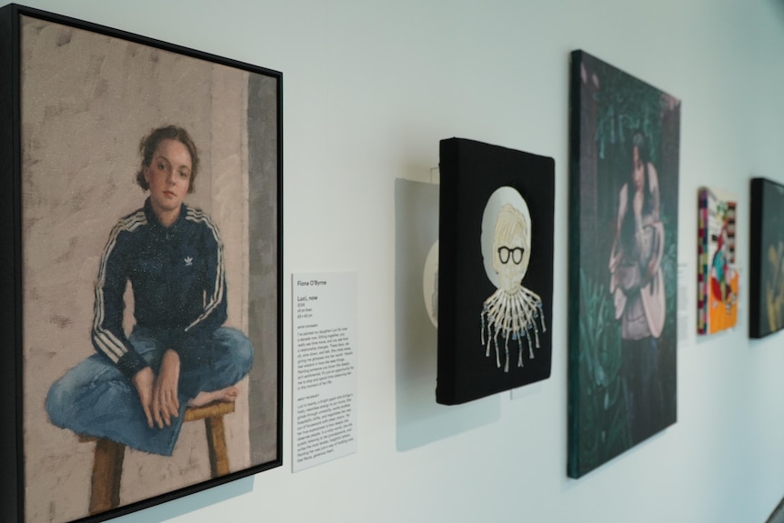 A painting of a girl is hung next to four others on a gallery wall.