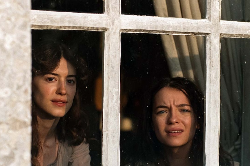 two sisters look out a window