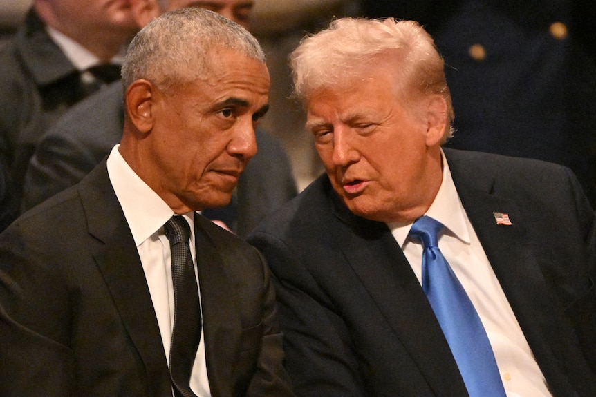 Barack Obama and Donald Trump, both dressed in dark suits, sit next to each other at a funeral.