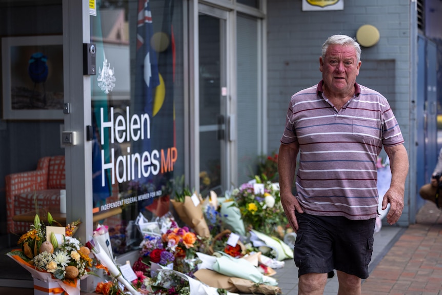 Bouquets of flowers adorn a glass window on a streetscape.