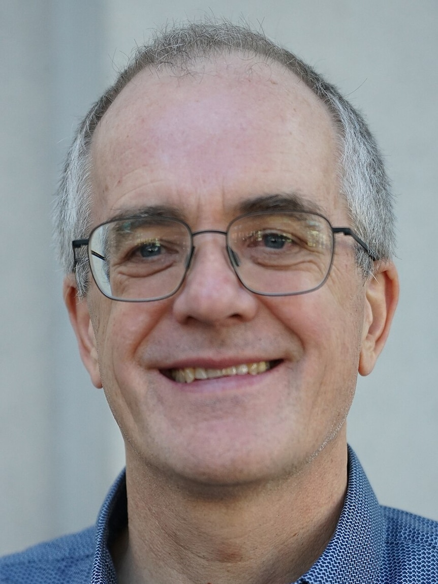 A man with glasses smiling