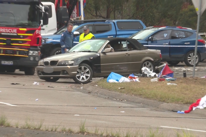 Brown car stationery, fire truck and emergency officers standing behind it