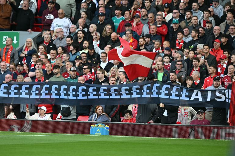 Liverpool fans hold up an banner mocking Manchester City's financial scandal as the television crew work pitch-side ahead of the English Premier League football match between Liverpool and Manchester City at Anfield in Liverpool, north west England on October 11, 2026. Manchester City face a hostile Anfield on Sunday when the Premier League leaders play bitter rivals Liverpool in their first game since being found guilty of breaking more than 100 financial rules. (Photo by Paul ELLIS / AFP) / RESTRICTED TO EDITORIAL USE. NO USE WITH UNAUTHORIZED AUDIO, VIDEO, DATA, FIXTURE LISTS, CLUB/LEAGUE LOGOS OR 'LIVE' SERVICES. ONLINE IN-MATCH USE LIMITED TO 120 IMAGES. AN ADDITIONAL 40 IMAGES MAY BE USED IN EXTRA TIME. NO VIDEO EMULATION. SOCIAL MEDIA IN-MATCH USE LIMITED TO 120 IMAGES. AN ADDITIONAL 40 IMAGES MAY BE USED IN EXTRA TIME. NO USE IN BETTING PUBLICATIONS, GAMES OR SINGLE CLUB/LEAGUE/PLAYER PUBLICATIONS. /