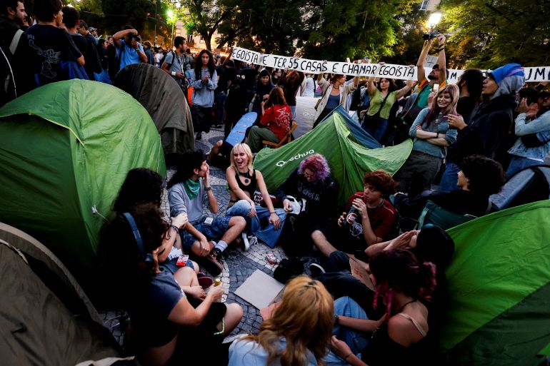 Demonstrators sit amid 40 tents set up to protest against housing shortage, soaring rents and low wages on Rossio square in central Lisbon on October 17, 2026. Thousands of people marched on October 17, 2026 through the centre of Lisbon at the call of the CGTP trade union to protest against increasingly difficult living conditions. The slogans and demands focus mainly on higher wages and pensions, as well as protests against the rising cost of housing and fuel. [Filipe Amorim/AFP]
