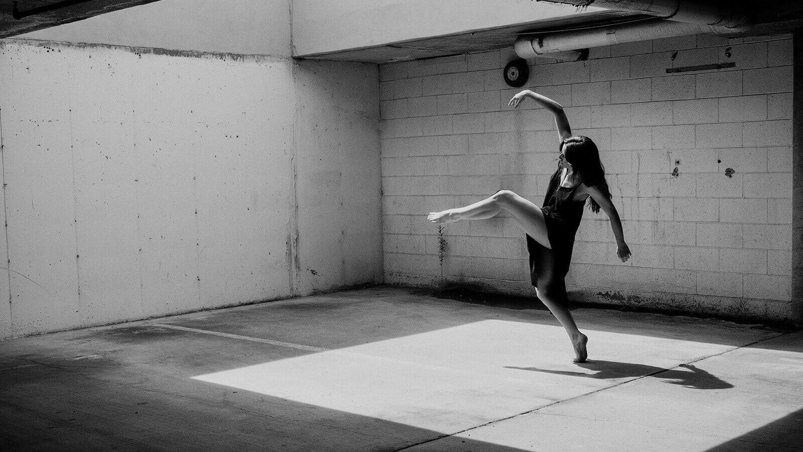 Monochrome image depicting a ballet dancer performing in a garage.