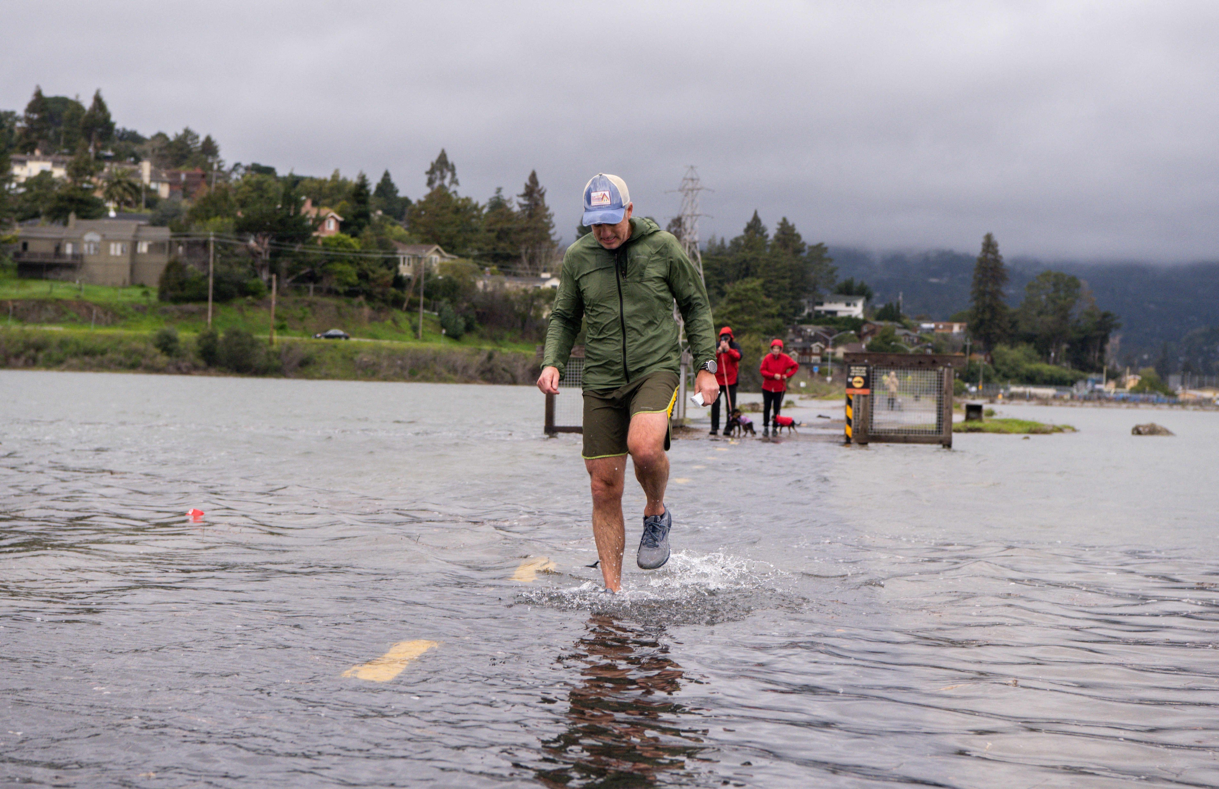 A jogger makes his way along a flooded Mill Valley bike path during a king tide event in January 2022. This year, the king tides are expected to be even worse than normal