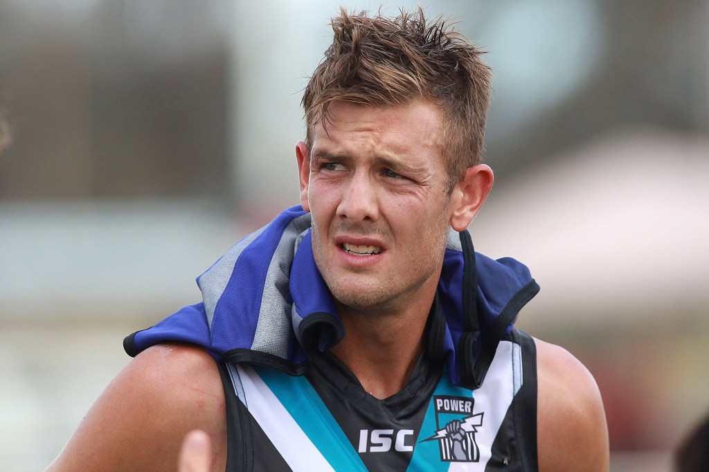 Port Adelaide player with a jacket over his shoulders during a match.