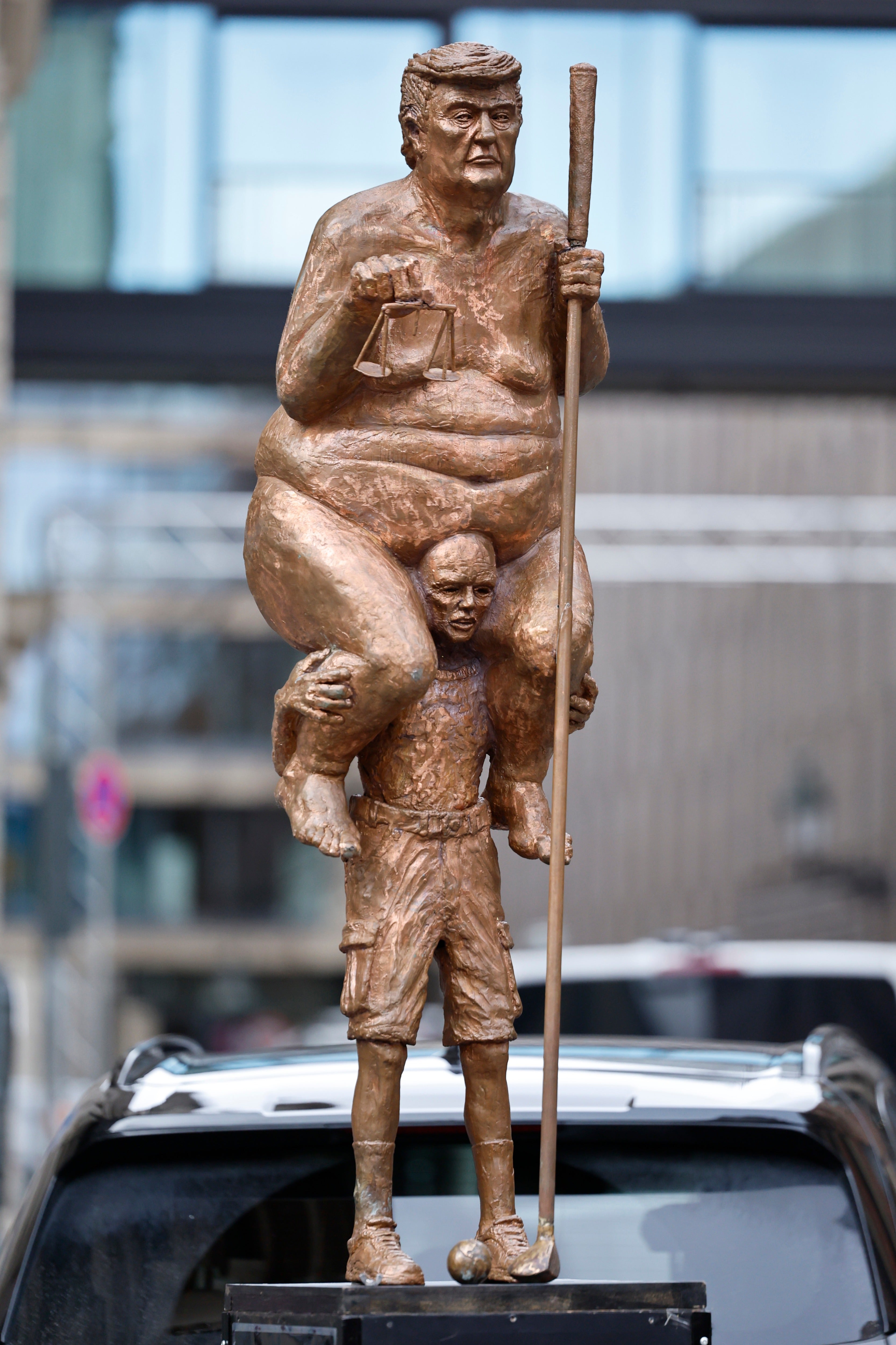 Showing him naked and balanced atop a far smaller man, the statue labels the US president “The King of Injustice”