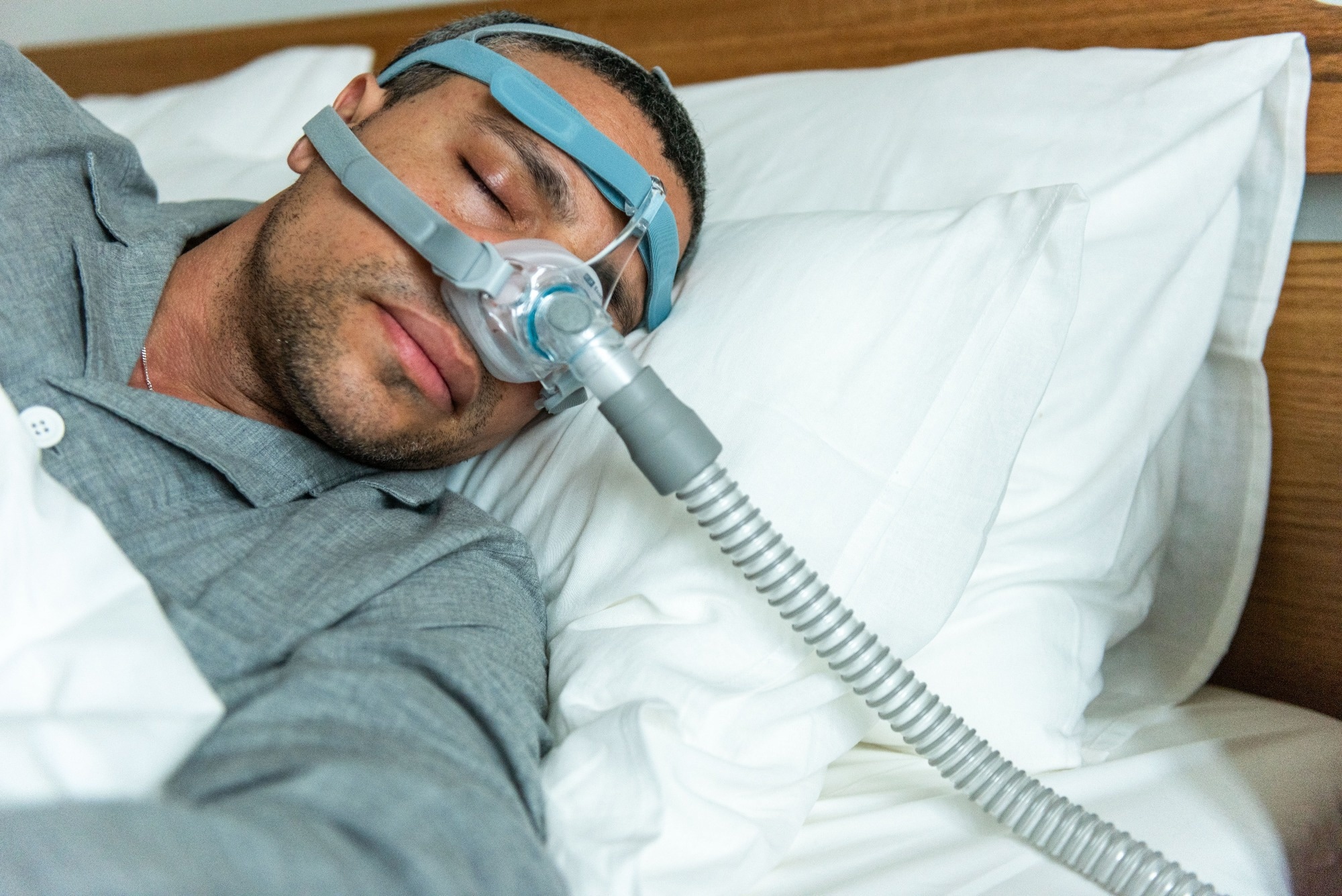 A person sleeps in bed wearing a CPAP mask for sleep apnea