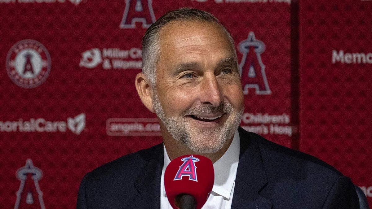 John Mozeliak stands at a press conference in Anaheim