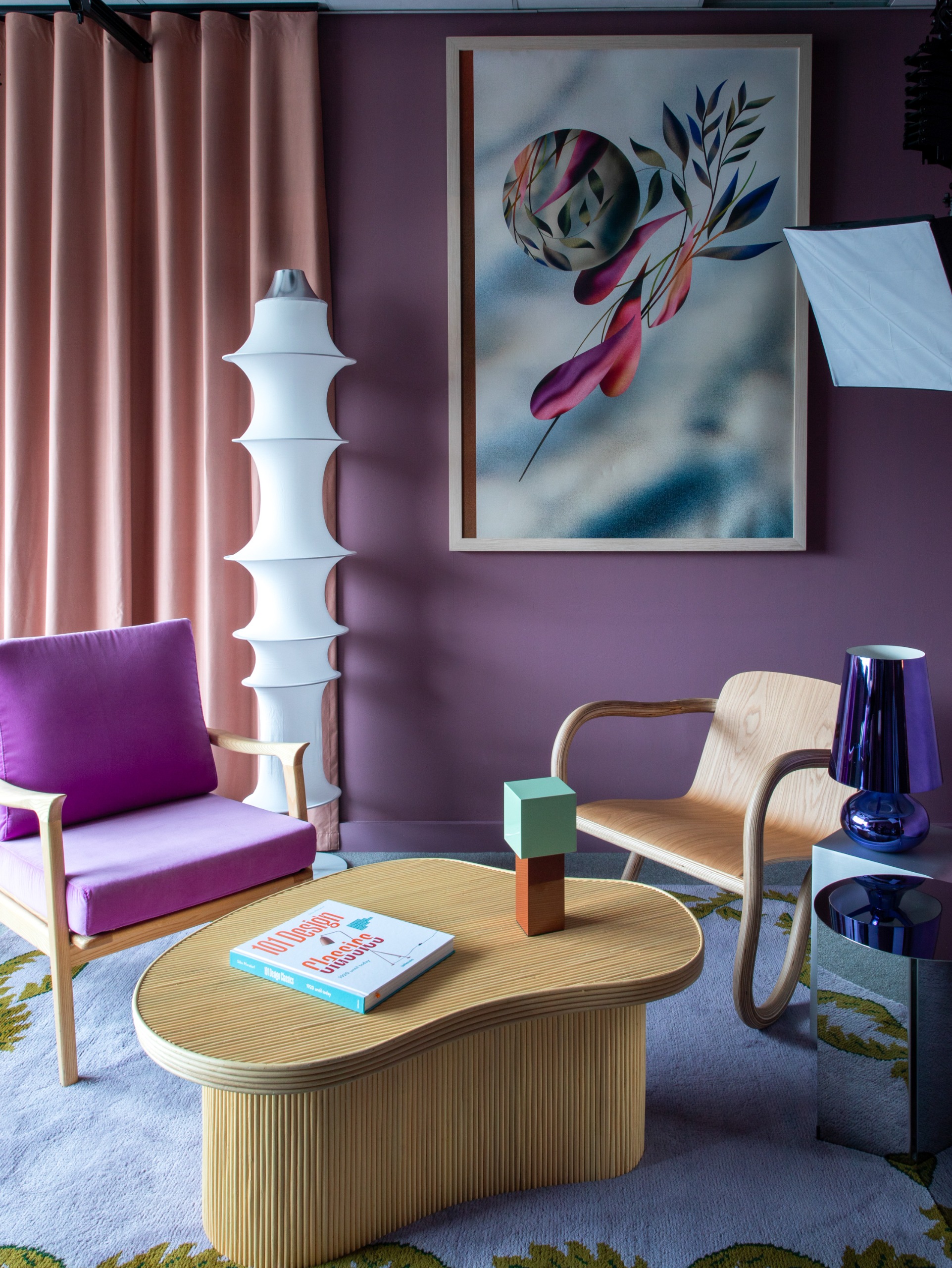 a small podcast studio with purple walls, lilac curtains and light wooden furniture