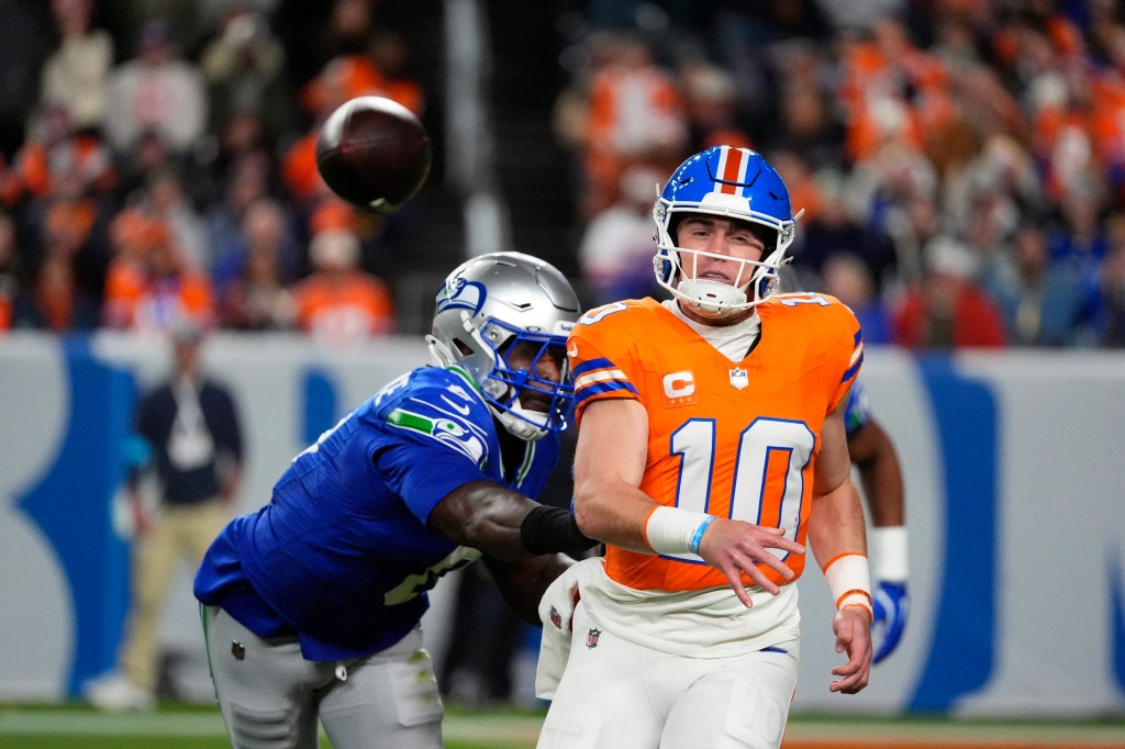 Denver Broncos quarterback Bo Nix passes the ball while under pressure from a Seattle Seahawks defender.