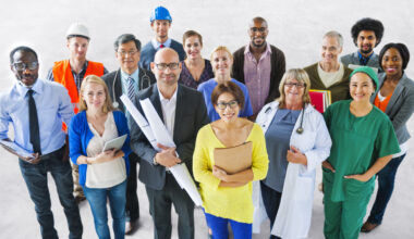 A group of diverse people of different professions in their work uniforms, smiling.