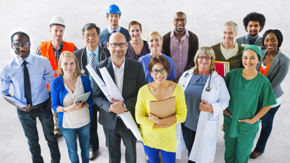 A group of diverse people of different professions in their work uniforms, smiling.