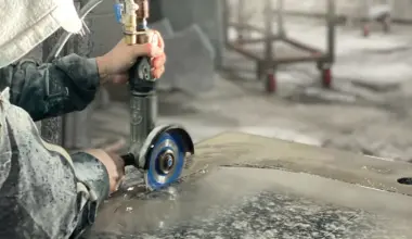 A person using a circular grinder to cut a hole in a countertop.