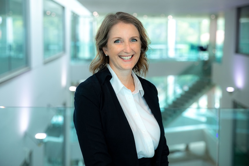 A woman in business attire smiles at the camera.
