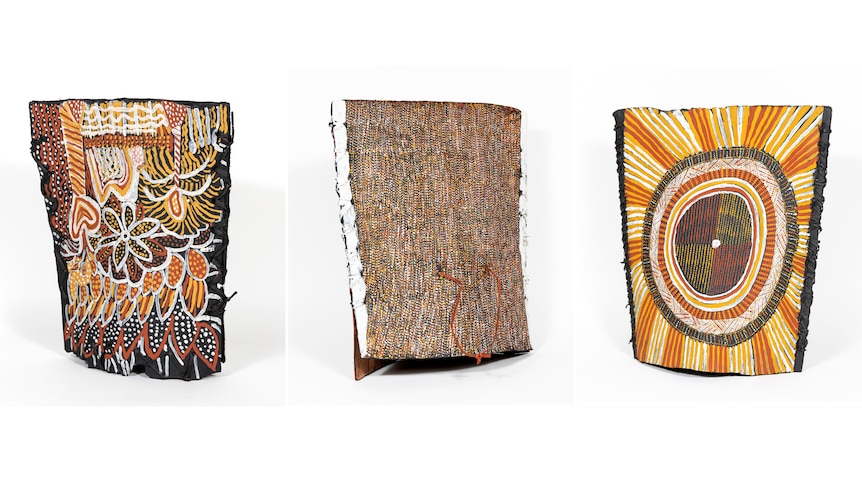 Three large bark bag sculptures decorated with bright ochre patterns