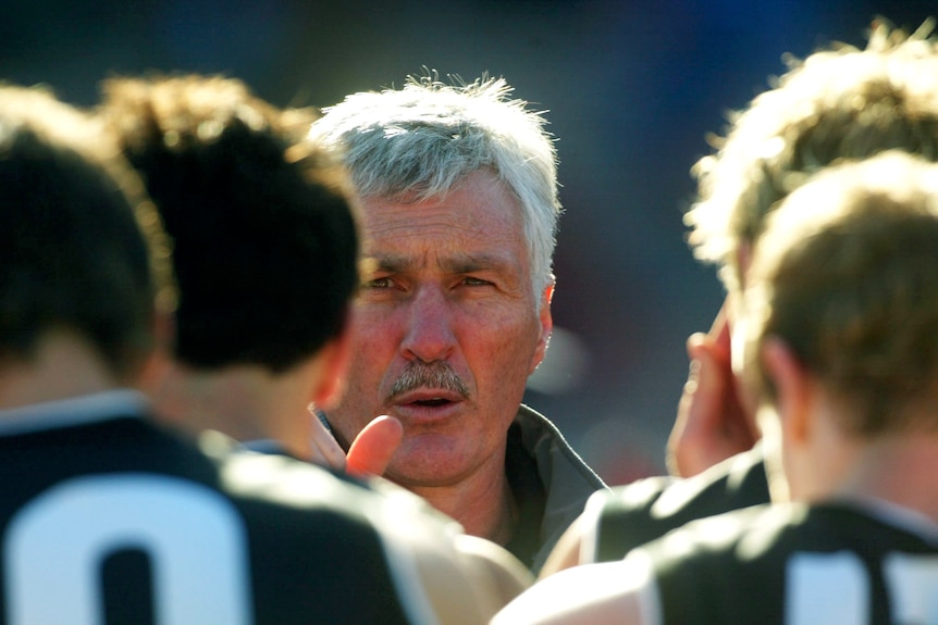 A picture of a coach talking to his team between quarters, taken from between the players facing him.  