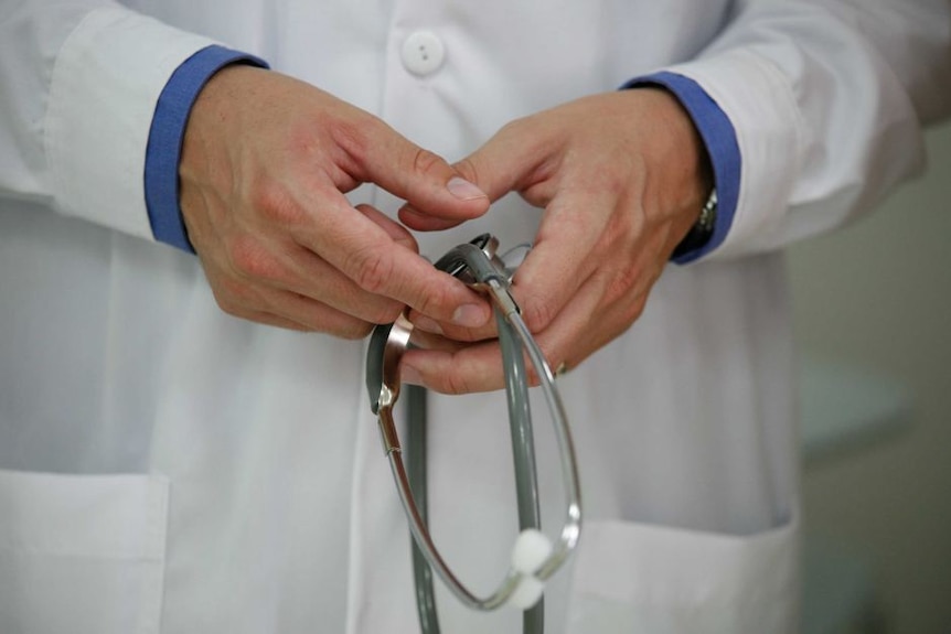 A doctor's hands in a white coat holding a stethoscope.