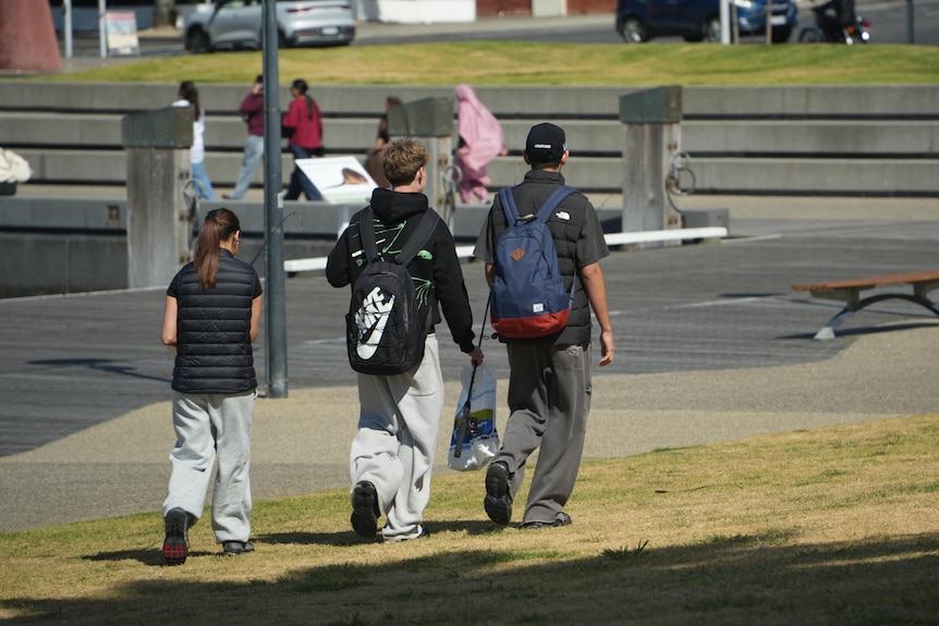 a trio of teens holding fishing gear walk through Geelong